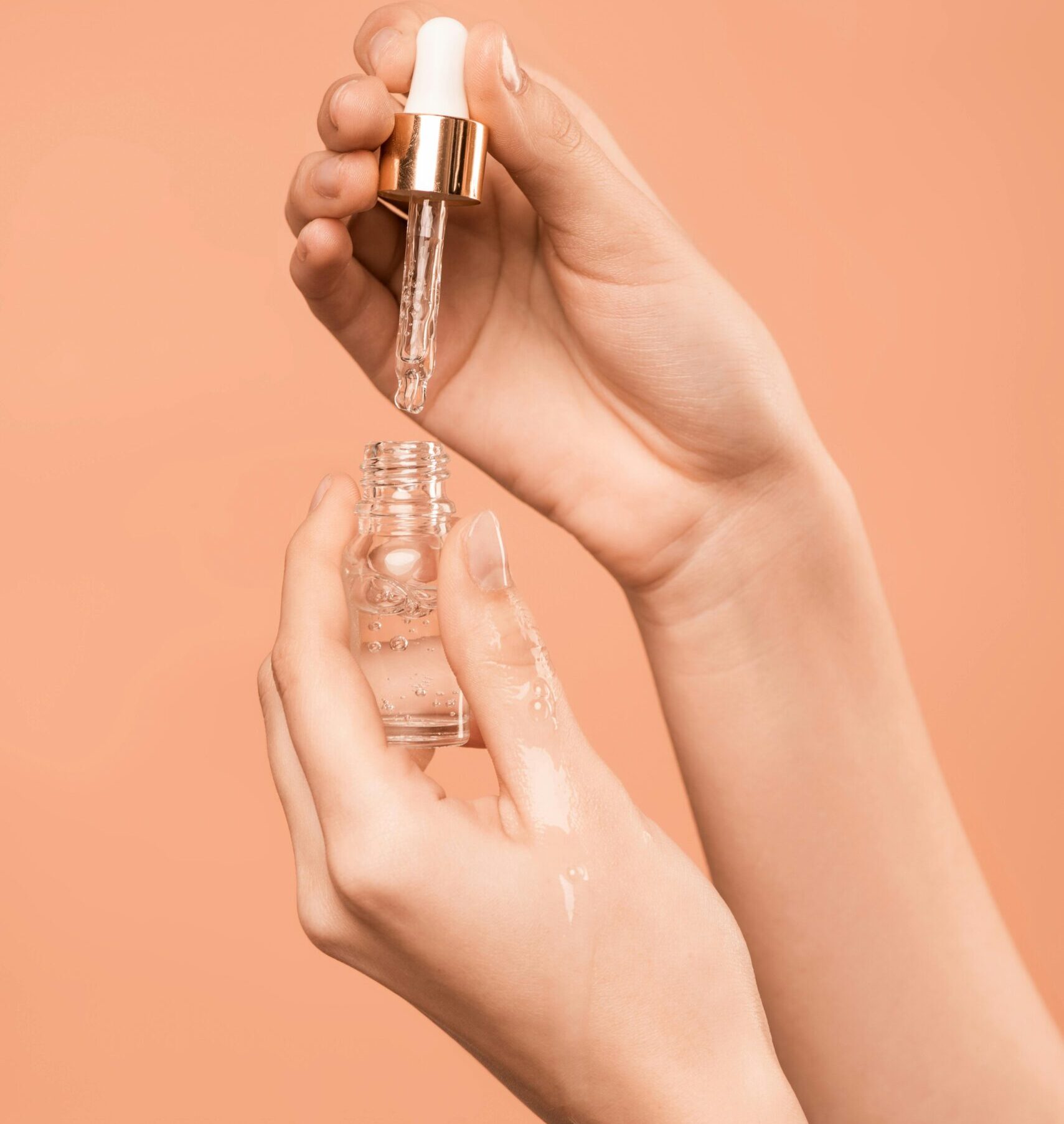 Close-up of hands using a dropper to apply skincare serum, ideal for health and beauty content.